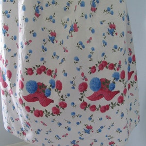 May include: White cotton fabric with a repeating pattern of pink flowers and blue birds. The fabric has a scalloped edge.