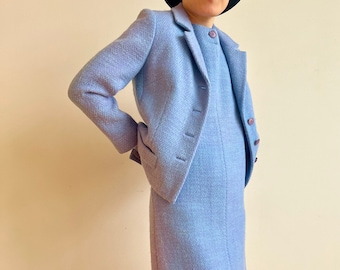 May include: A light blue suit with a matching jacket and skirt. The jacket has a single button closure and the skirt is knee-length.