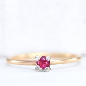 Op de afbeelding: Een delicate gouden ring met een enkele robijn-edelsteen gezet in een vier-klauw-setting.