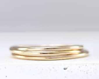 Puede incluir: Tres anillos apilables de oro, cada uno con una superficie lisa y redondeada. Los anillos están apilados uno encima del otro, creando un aspecto simple y elegante.