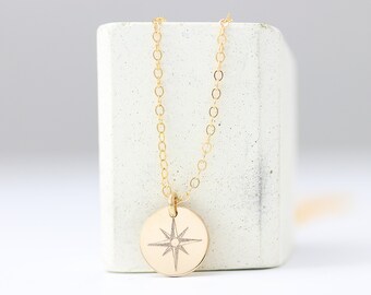 May include: A gold necklace with a round pendant featuring a compass rose design.