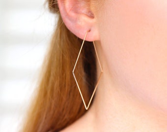 May include: A pair of gold diamond-shaped hoop earrings. The earrings are simple and elegant, and would make a great gift for any occasion.