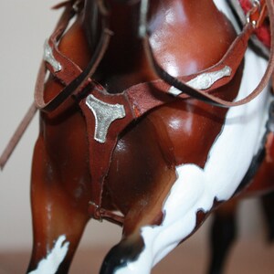 Puede incluir: Primer plano de un caballo marr&oacute;n y blanco con una brida de cuero marr&oacute;n y detalles plateados. La brida tiene una hebilla plateada decorativa.