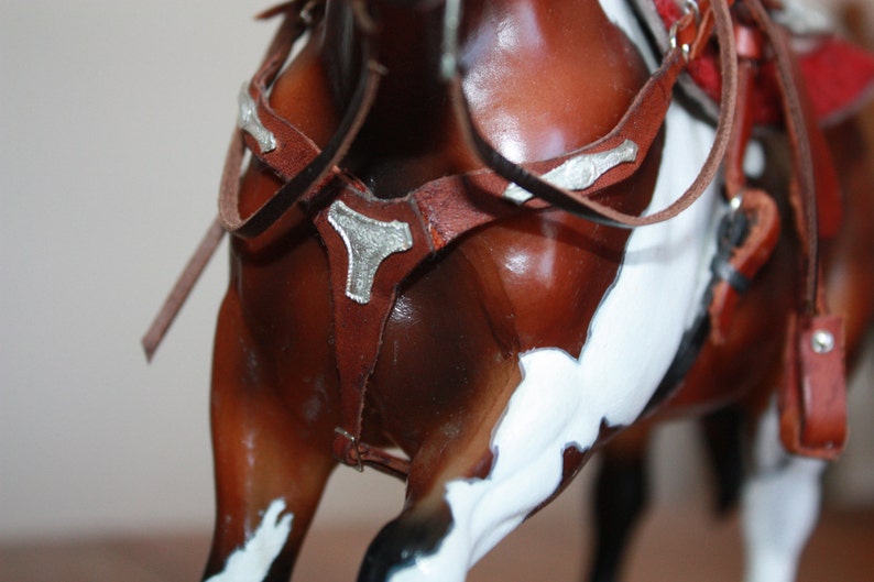 Puede incluir: Primer plano de un caballo marr&oacute;n y blanco con una brida de cuero marr&oacute;n y detalles plateados. La brida tiene una hebilla plateada decorativa.