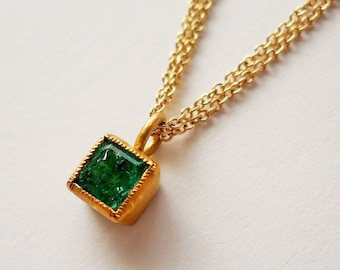 May include: A gold chain necklace with a square green gemstone pendant.