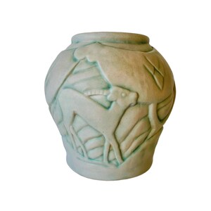 May include: A light green ceramic vase with a raised design of stylised animals. The vase has a rounded body and a slightly flared lip.