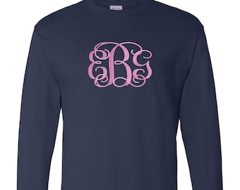 May include: A navy blue long-sleeved t-shirt with a pink monogram of the letters "B C G" on the front.
