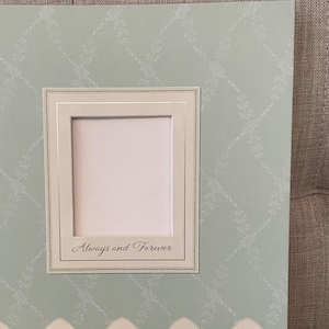 May include: A light blue scrapbook with a white frame and the text "Always and Forever". The scrapbook has a decorative border with a floral design.