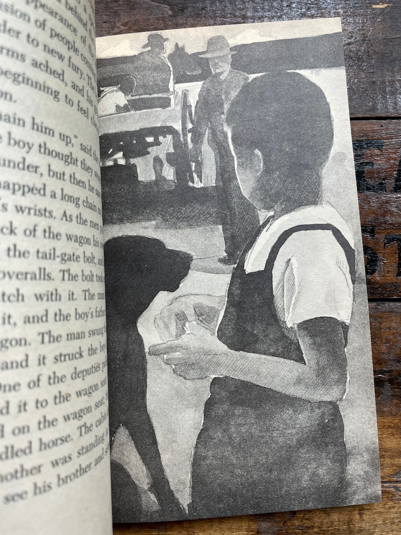 May include: A black and white illustration of a boy holding a dog. The boy is wearing a white shirt and dark pants. The dog is looking at the boy. In the background, there are three men standing near a wagon.