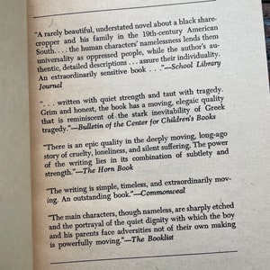 May include: A close-up of a book page with text about a novel. The text highlights the book's themes of tragedy, cruelty, and quiet strength. The book is described as "rarely beautiful" and "extraordinarily sensitive".