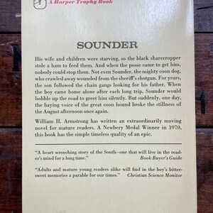 May include: A vintage book cover with a yellow background and brown text. The title of the book is "Sounder" and the author is William H. Armstrong. The book is a Newbery Medal Winner from 1970. The back cover includes quotes from Book Buyer's Guide and Christian Science Monitor.