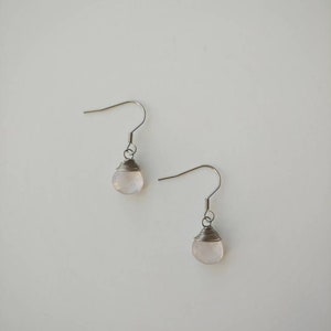 May include: A pair of silver earrings with a light pink gemstone on each earring.
