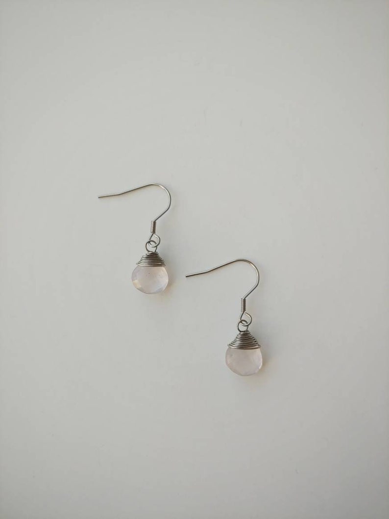 May include: A pair of silver earrings with a light pink gemstone on each earring.