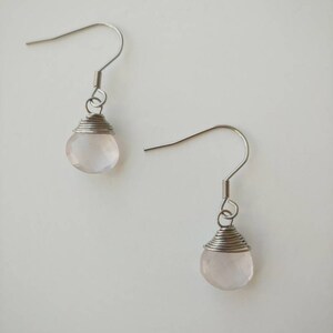 May include: A pair of silver earrings with pink rose quartz stones.