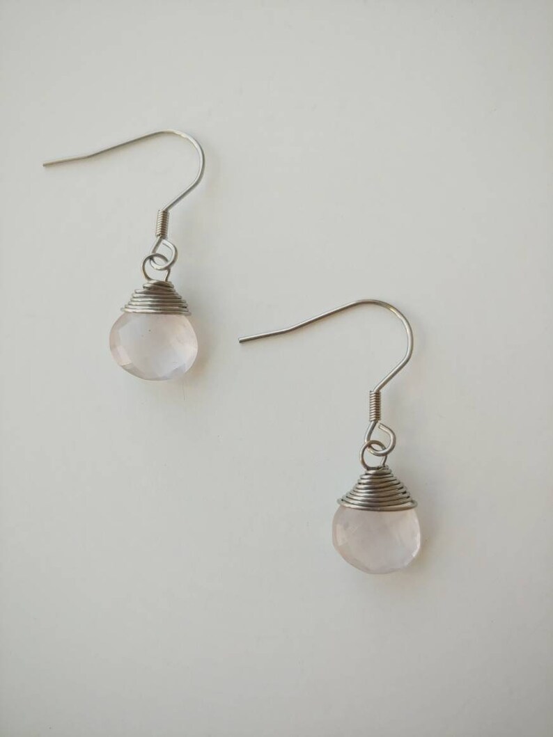 May include: A pair of silver earrings with pink rose quartz stones.