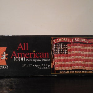 May include: A black box with a red and white American flag made of Campbell's Soup cans. The box says "All American 1000 Piece Jigsaw Puzzle" and "Campbell's Soups 6 Plaines 10c".