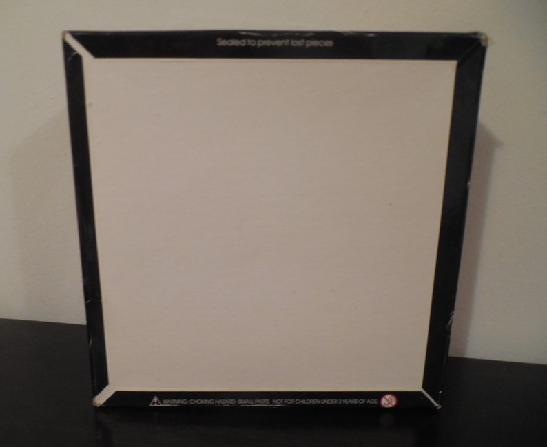 May include: A black box with white text that reads "Sealed to prevent lost pieces". The bottom of the box has a warning label that reads "WARNING: CHOKING HAZARD - SMALL PARTS. NOT FOR CHILDREN UNDER 3 YEARS OF AGE."