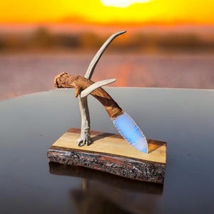 May include: A blue and white opal knife with a wooden handle is displayed on a wooden stand with antler accents.