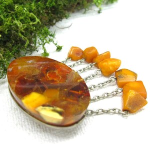 Puede incluir: Un broche vintage de &aacute;mbar con una piedra grande de &aacute;mbar de forma ovalada y una cadena de plata con cuentas de &aacute;mbar m&aacute;s peque&ntilde;as que cuelgan.