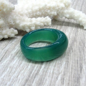 May include: A smooth, green agate ring with a rounded, polished surface.