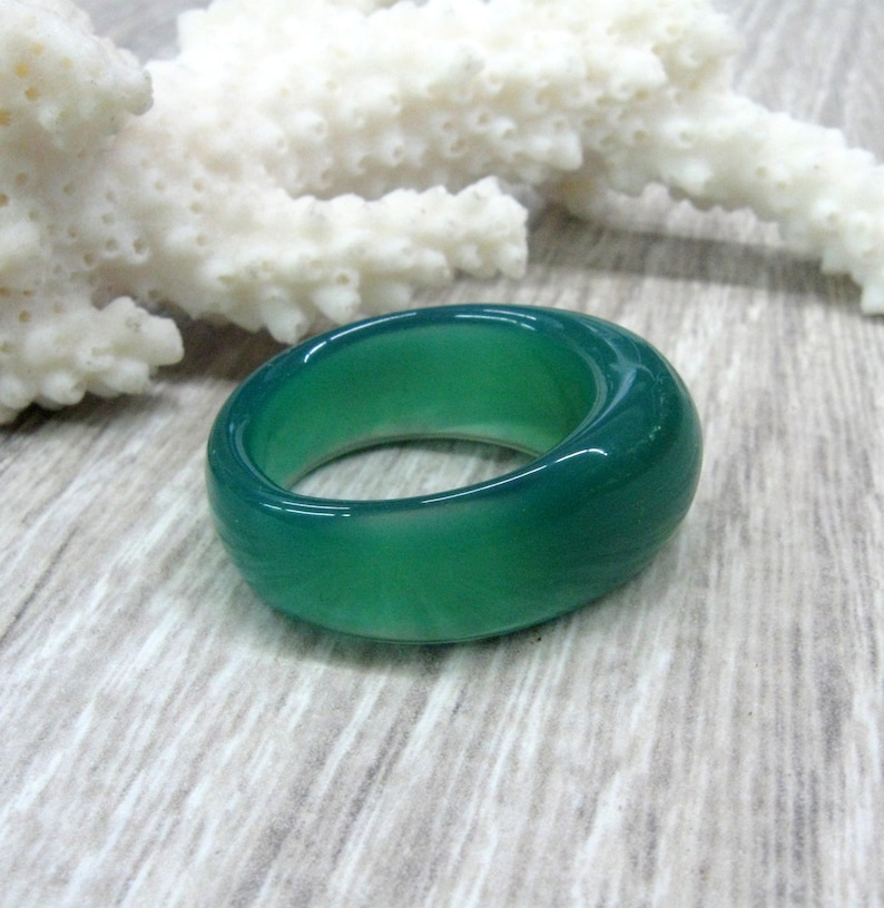 May include: A smooth, green agate ring with a rounded, polished surface.