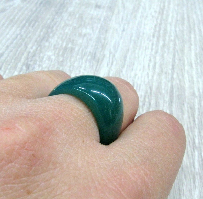 May include: A dark green ring made of polished stone. The ring is thick and has a rounded shape.