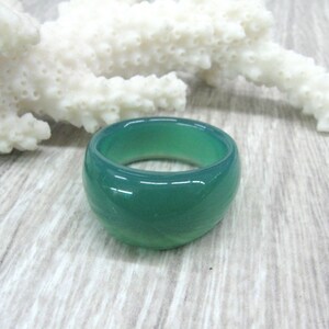 May include: A wide green agate ring with a smooth, polished finish.