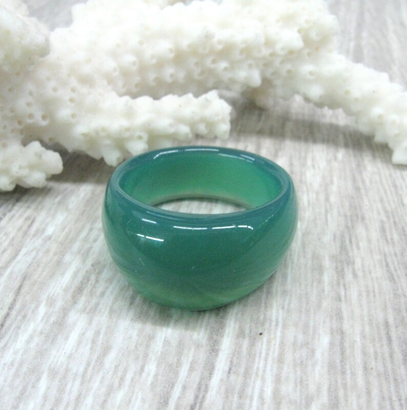 May include: A wide green agate ring with a smooth, polished finish.