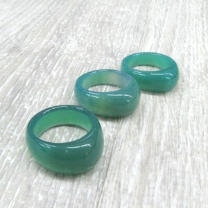 May include: Three green agate rings, each with a smooth, rounded surface. The rings are arranged in a row, with the largest ring at the top and the smallest ring at the bottom.