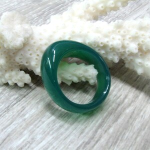 May include: A smooth, green jade ring with a polished finish. The ring is oval shaped and has a simple design.