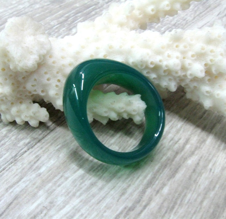 May include: A smooth, green jade ring with a polished finish. The ring is oval shaped and has a simple design.