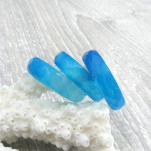 May include: Three blue agate rings stacked on top of each other. The rings are faceted and have a light blue color.