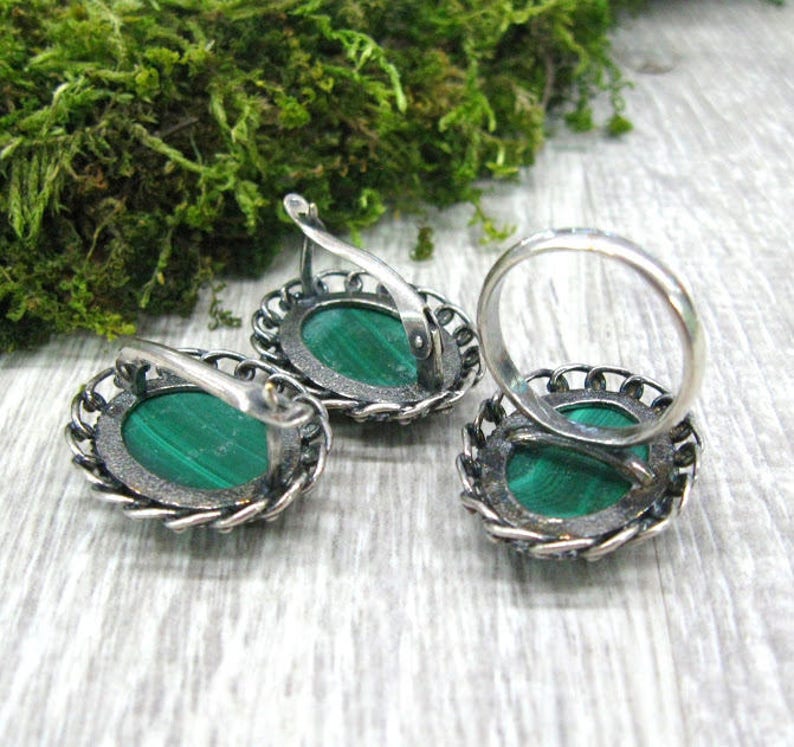May include: A set of silver earrings and a ring with green malachite stones. The earrings have a delicate filigree design and the ring has a simple band.