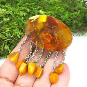 Puede incluir: Un broche vintage de &aacute;mbar con una gran piedra ovalada de &aacute;mbar y una cadena de plata con piedras de &aacute;mbar m&aacute;s peque&ntilde;as que cuelgan.