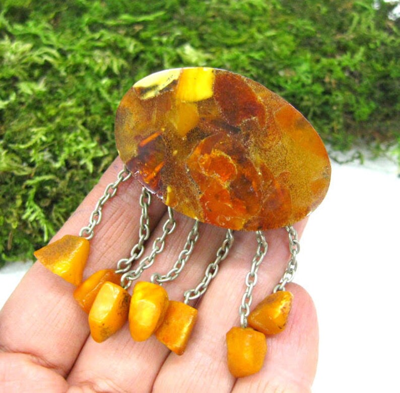 Puede incluir: Un broche vintage de &aacute;mbar con una gran piedra ovalada de &aacute;mbar y una cadena de plata con piedras de &aacute;mbar m&aacute;s peque&ntilde;as que cuelgan.