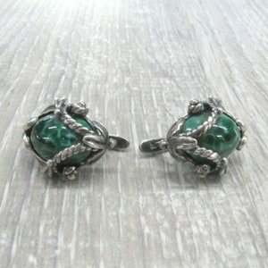 May include: A pair of silver earrings with green malachite stones set in intricate silver designs.
