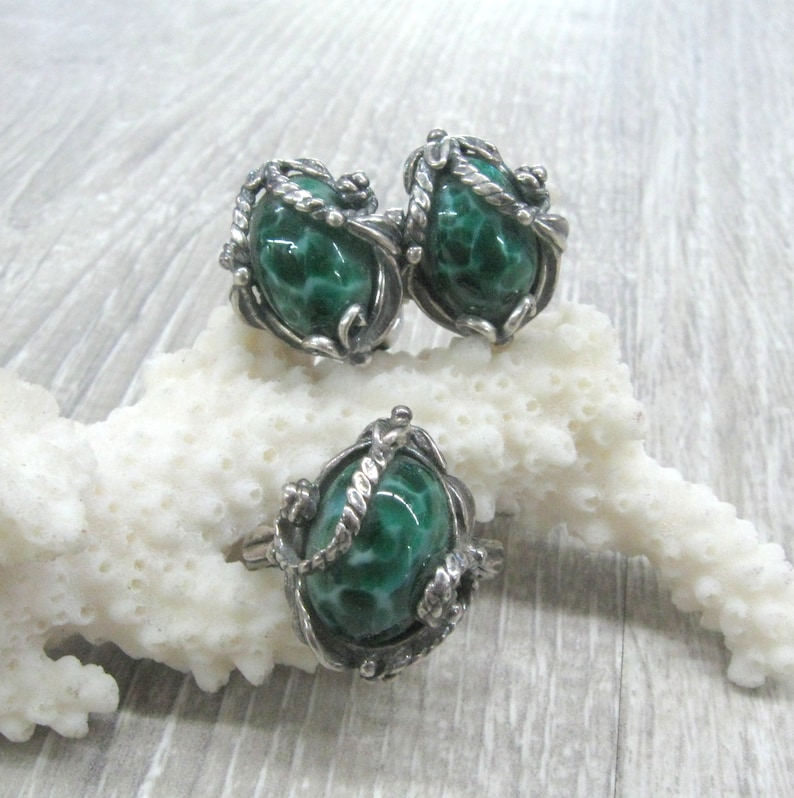 May include: A set of silver earrings and a ring with green malachite stones. The stones are set in a silver filigree design.