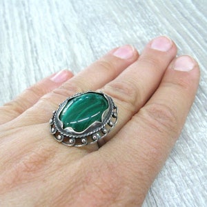 May include: A silver ring with a green malachite stone set in an ornate design.