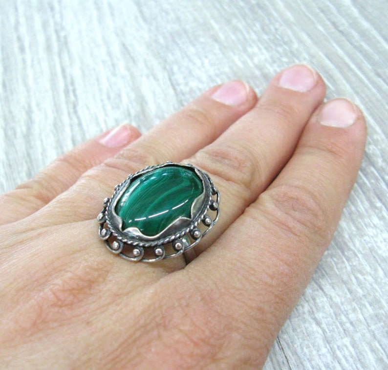May include: A silver ring with a green malachite stone set in an ornate design.