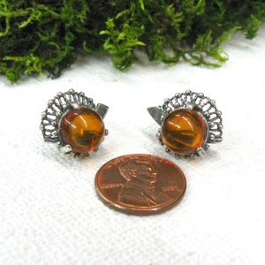 May include: A pair of silver earrings with amber stones. The earrings have a delicate filigree design.