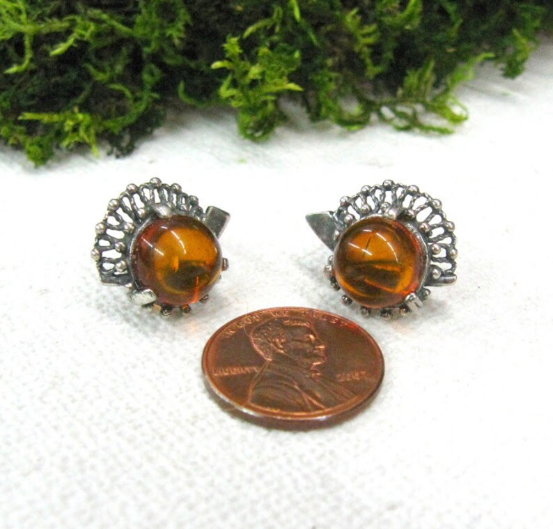 May include: A pair of silver earrings with amber stones. The earrings have a delicate filigree design.