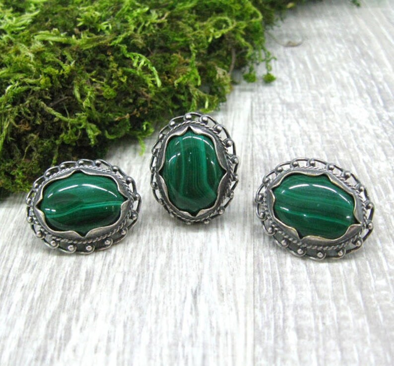May include: A set of three silver rings with green malachite stones. The rings have a delicate, ornate design.