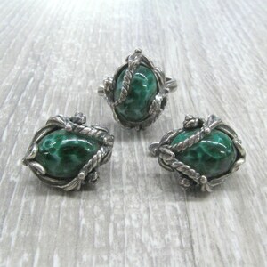 May include: A set of silver earrings and a ring with green malachite stones. The stones are set in a detailed silver design.