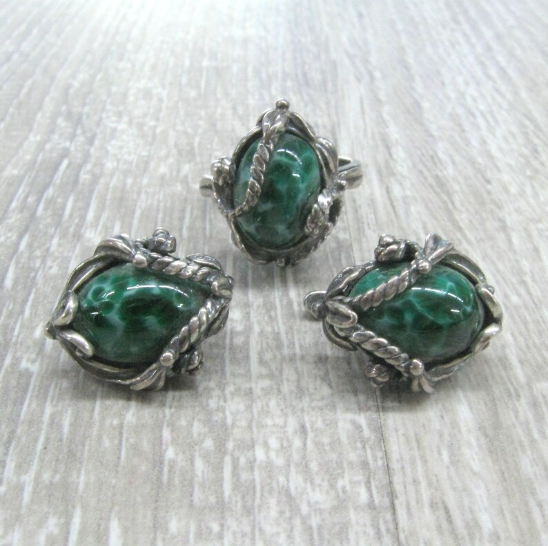 May include: A set of silver earrings and a ring with green malachite stones. The stones are set in a detailed silver design.