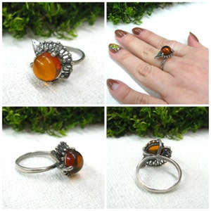 May include: A silver ring with an amber stone set in a delicate filigree design. The ring is shown from multiple angles.