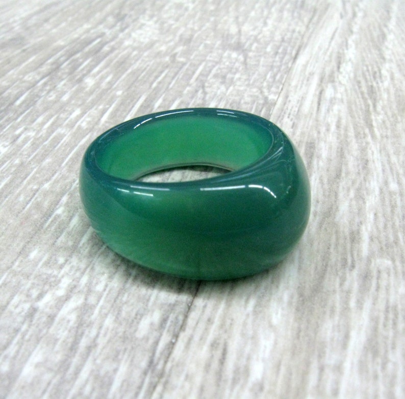 May include: A smooth, green gemstone ring. The ring is made of a single, oval-shaped stone.