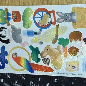 Puede incluir: Una hoja de pegatinas con temática de mascotas. Las pegatinas presentan varios animales, como un loro, un hámster, un conejo y un pez. Otras pegatinas incluyen un lagarto, un ratón y un conejillo de indias. Acabado iridiscente.
