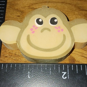 May include: A brown monkey eraser with a smiling face, pink cheeks, and black eyes.