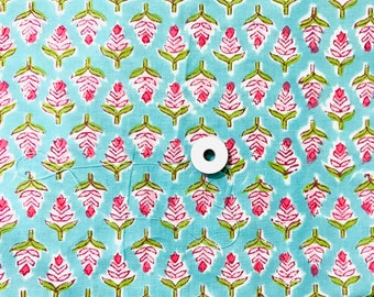 以下が含まれることがあります： ピンクの花柄の青い布の上に置かれた白い糸巻き