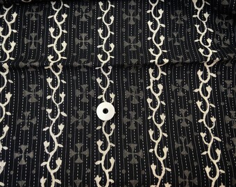 May include: Black fabric with a white floral pattern and a repeating cross design. The fabric has a subtle texture and is perfect for quilting or other craft projects.